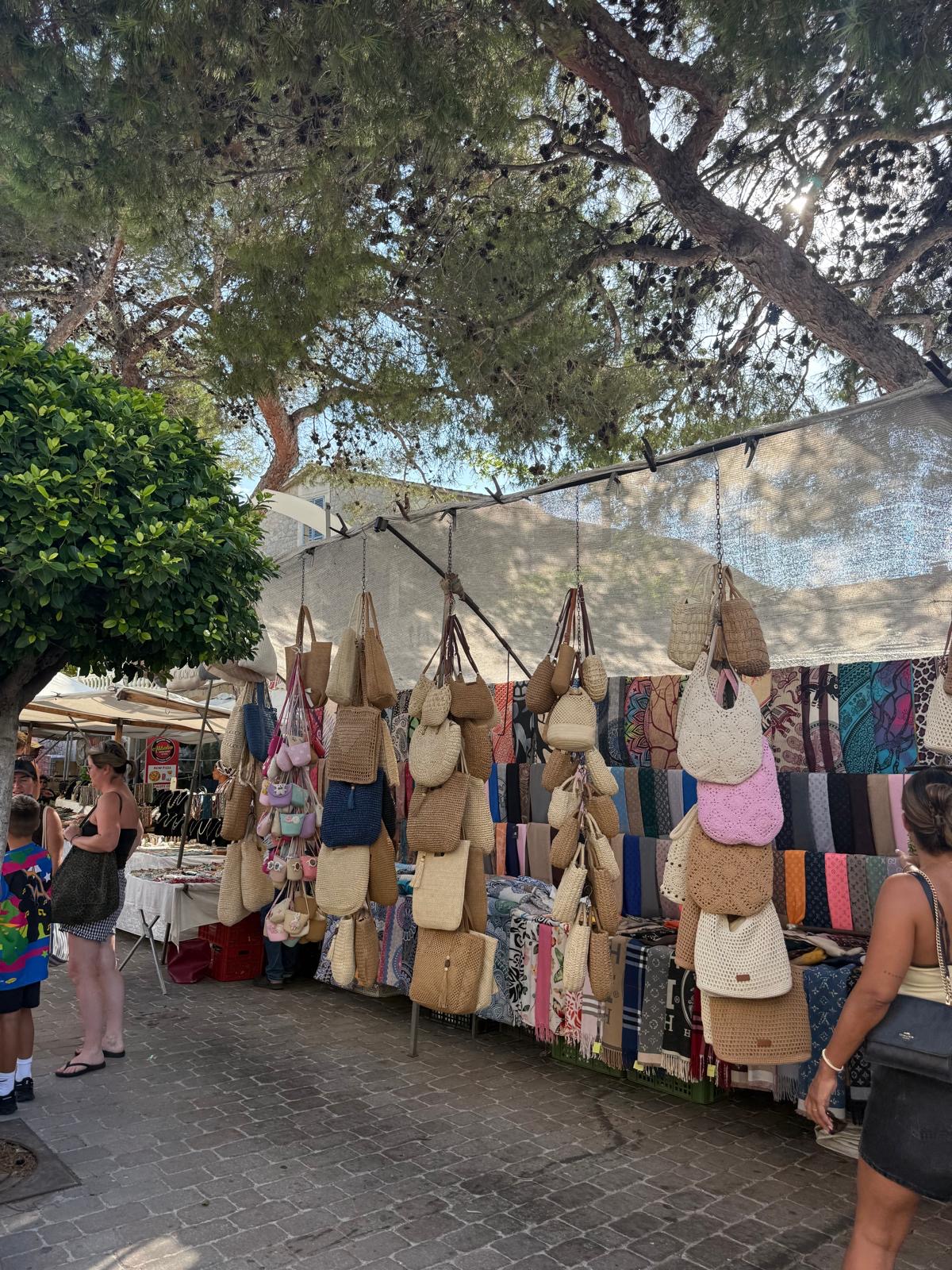 Korbtaschen und Tücher unter Pinien auf dem Markt in Artà