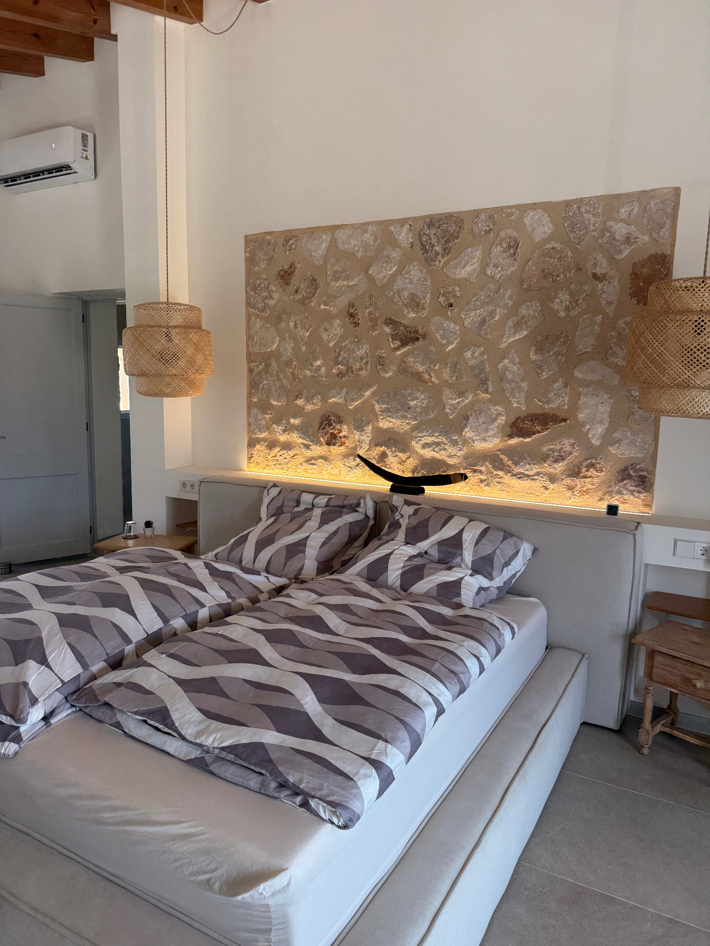 Studio · Bett vor der Natursteinwand